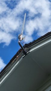 External antenna mounted at the roof edge with its cabling run down behind the gutter
